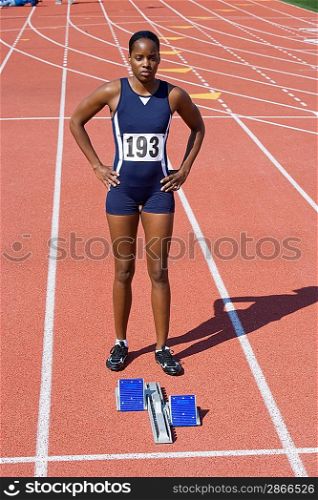 Female athlete next to starting block, ready to run