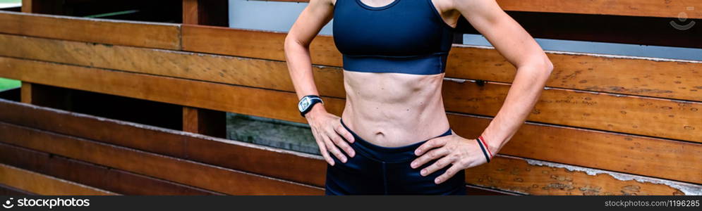 Female athlete posing in front of a wooden background. Cheerful female athlete in front of a wooden background