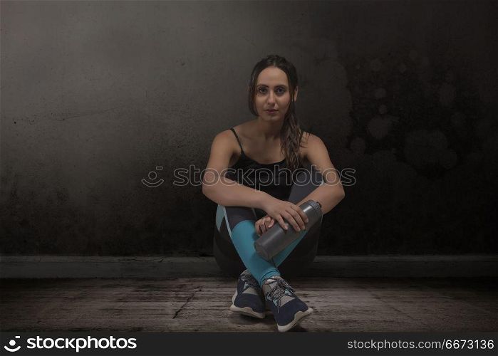 Female athlete sitting legs crossed with water bottle on floor