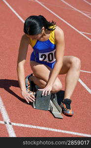 Female athlete stetting up starting block