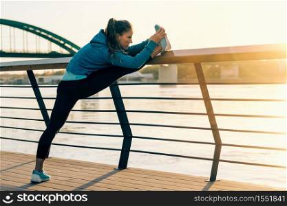 Female athlete streching outdoors by the riverside