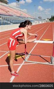 Female athlete stretching on hurdle