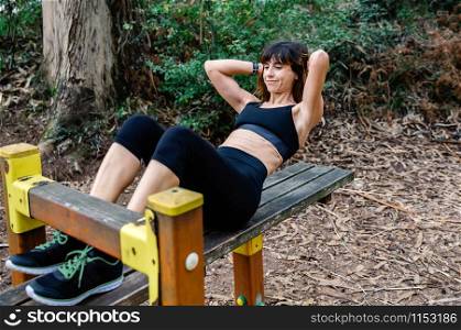 Female athlete training on an abdominal bench outdoors. Sportswoman training on an abdominal bench