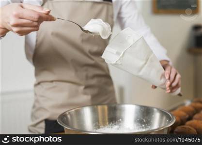 female baker filling whipped cream white icing bag. High resolution photo. female baker filling whipped cream white icing bag. High quality photo