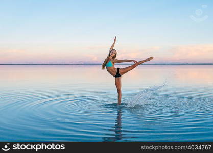 Female ballet dancer poised on one leg in lake, Bonneville Salt Flats, Utah, USA