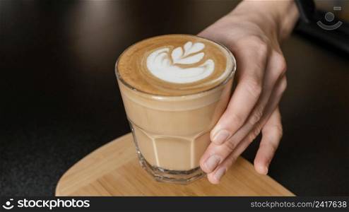female barista holding decorated coffee glass