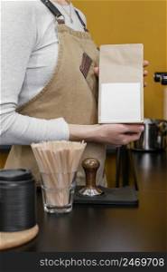 female barista holding paper coffee bag