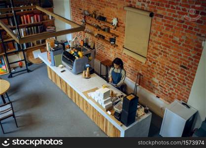 Female barista in apron take orders in cafe. Woman makes fresh espresso in cafeteria, waiter prepares coffee at the counter in bar, top view. Female barista in apron take orders in cafe