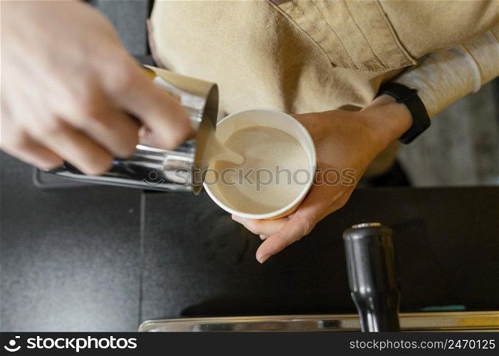 female barista pouring frothed milk cup