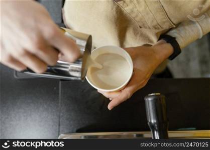 female barista pouring frothed milk cup