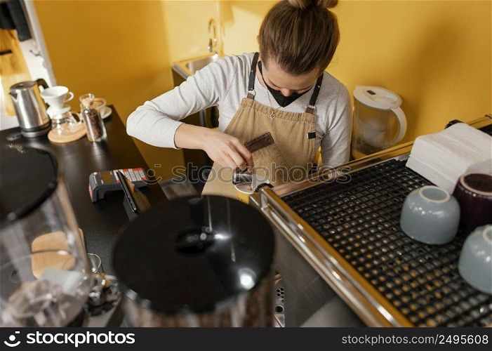 female barista with mask working coffeehouse