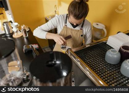 female barista with mask working coffeehouse