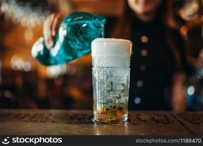 Female barman pours aerated water into a glass. Woman bartender mixing at the bar counter in pub. Barkeeper occupation. Female barman pours aerated water into a glass