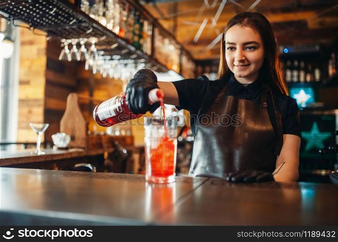 Female barman prepares alcoholic coctail with ice. Alcohol drink preparation. Woman bartender working at the bar counter in pub. Female barman prepares alcoholic coctail with ice