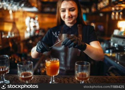 Female bartender holding a glass with coctail over the bar counter. Alcohol drink preparation. Barman working in pub. Female bartender holding a glass with coctail