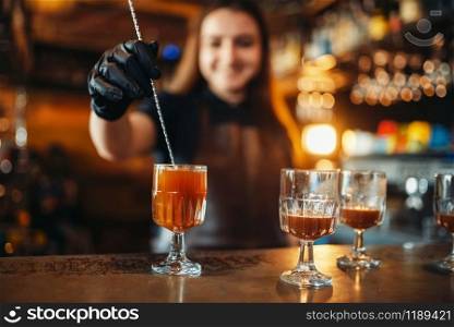Female bartender making coctail at the bar counter. Alcohol drink preparation. Barman working in pub. Female bartender making coctail at the bar counter