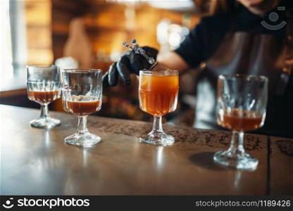 Female bartender prepares alcoholic coctail. Alcohol drink preparation. Barman working at the bar counter in pub. Female bartender prepares alcoholic coctail in pub