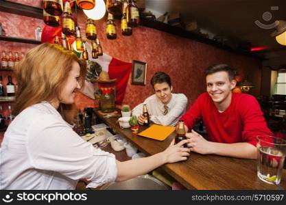 Female bartender serving beer to men at bar counter