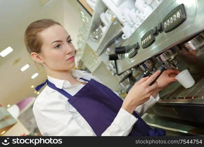 female bartender waiter in uniform making coffee at the bar