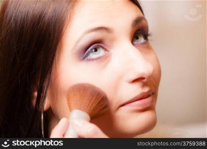 Female beauty. Makeup artist applying with brush powder or rouge on check of her client young woman. Girl by visagiste.