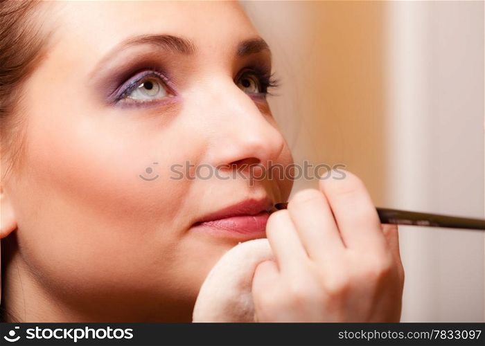 Female beauty. Makeup artist applying with pink lipstick lipgloss on lips of her client young woman. Girl by visagiste.