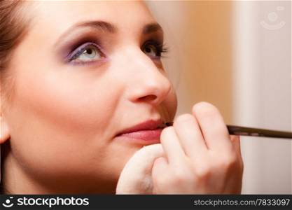 Female beauty. Makeup artist applying with pink lipstick lipgloss on lips of her client young woman. Girl by visagiste.