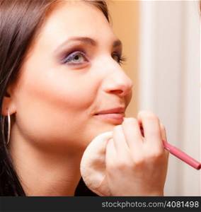 Female beauty. Makeup artist applying with pink pencil cosmetic on lips of her client young woman. Girl by visagiste.