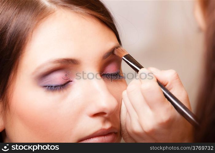 Female beauty. Makeup artist stylist applying with brush cosmetic on eyebrow of young woman. Girl by visagiste.