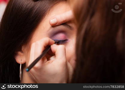 Female beauty. Makeup artist stylist applying with brush eyeshadow on eyelid of young woman. Girl by visagiste.