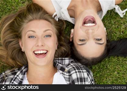 Female best friends lying on the grass and laughing