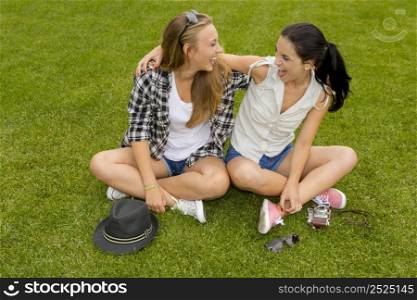 Female best friends sitting on the grass and having a good time