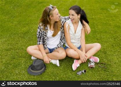 Female best friends sitting on the grass and having a good time