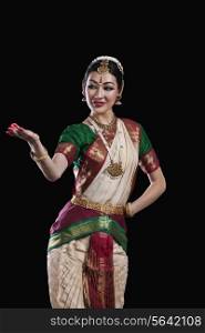 Female Bharat Natyam dancer performing over black background