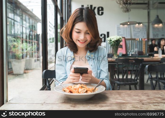 Female blogger photographing lunch in restaurant with her phone. A young woman taking photo of spaghetti food on smartphone, photographing meal with mobile camera.