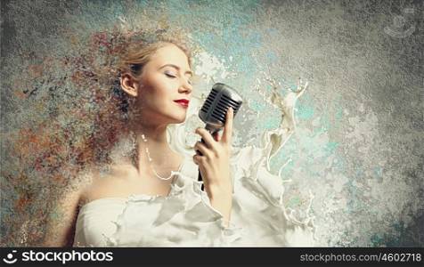 Female blonde singer. Image of female blonde singer holding microphone against color background with closed eyes