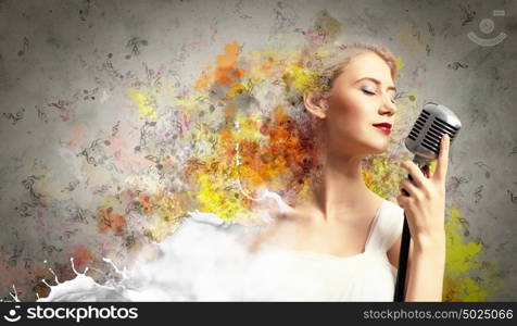 Female blonde singer. Image of female blonde singer holding microphone against color background with closed eyes