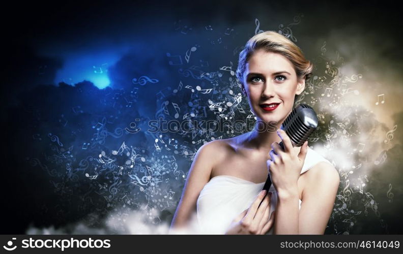 Female blonde singer. Image of female blonde singer holding microphone against smoke background