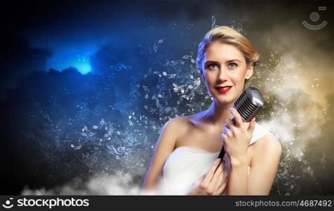Female blonde singer. Image of female blonde singer holding microphone against smoke background