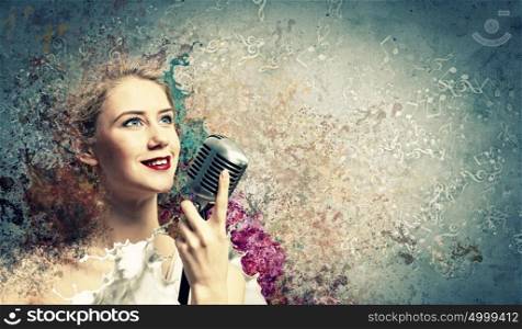 Female blonde singer. Image of female blondN? singer holding microphone against color background