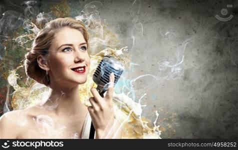 Female blonde singer. Image of female blondN? singer holding microphone against smoke background