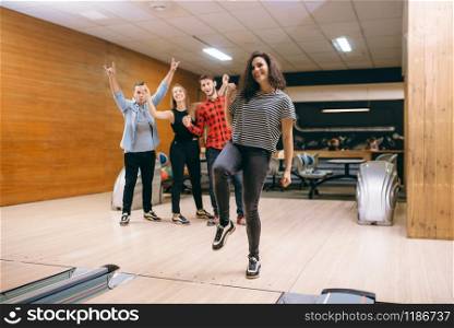 Female bowler throws ball on lane, strike shot. Bowling alley teams playing the game in club, active leisure. Female bowler throws ball on lane, strike shot