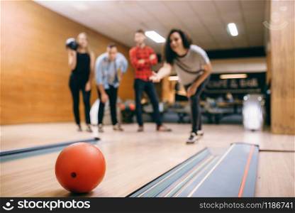 Female bowler throws ball on lane, strike shot. Bowling alley teams playing the game in club, active leisure