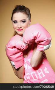Female boxer model wearing big fun pink gloves playing sports boxing studio shot, brown background