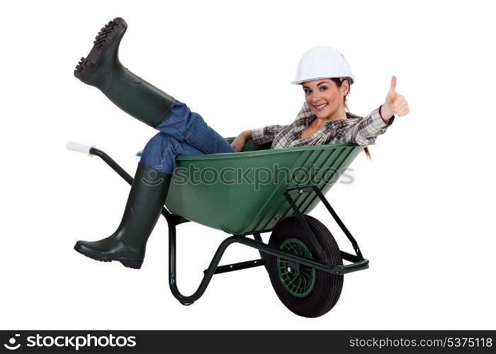 female bricklayer sitting in wheelbarrow thumb up