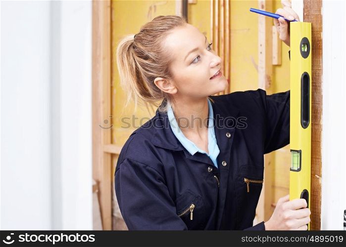 Female Builder Checking Work With Spirit Level
