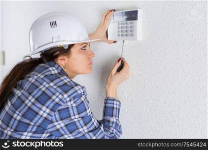 female builder fixing a wall thermostat