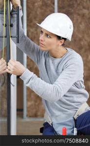 female builder measuring glass door
