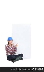 Female builder sat pointing