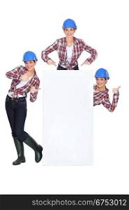 Female builder stood with blank poster