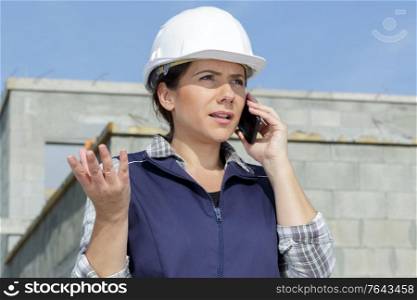 female builder unhappy on phone wearing a safety helmet